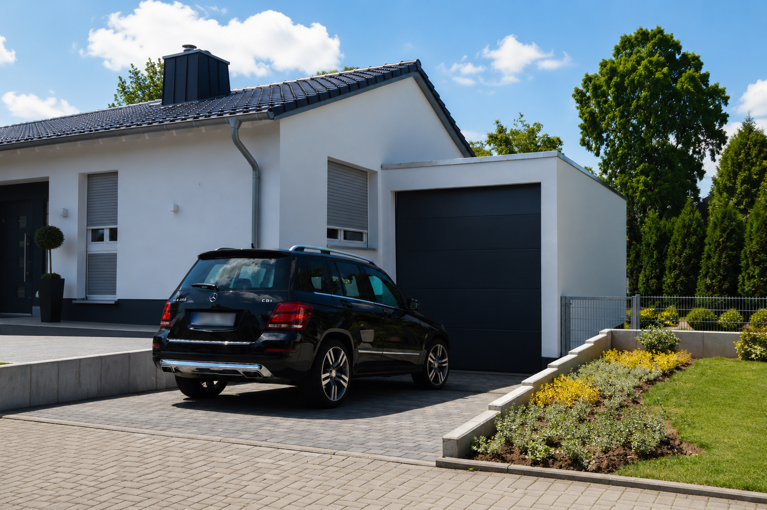Modernes Einfamilienhaus mit schwarzem SUV auf gepflasterter Einfahrt. Gepflegter Garten.