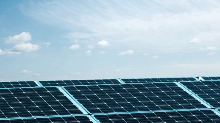 Solarpanel-Anlage unter blauem Himmel mit wenigen Wolken.