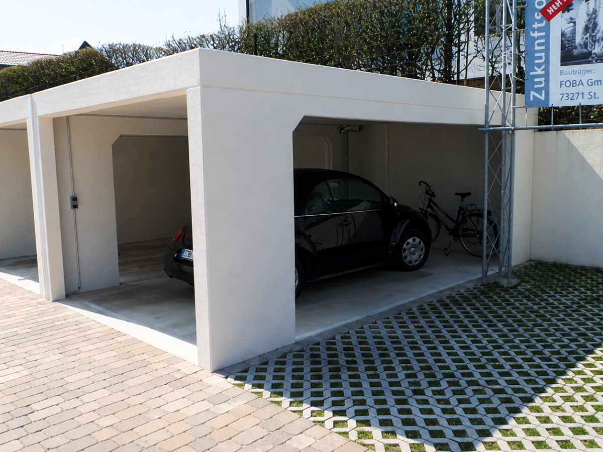 Reihenhausgarage mit drei Stellplätzen, ein Auto und ein Fahrrad darin. Vorgelagert gepflasterter Hof.