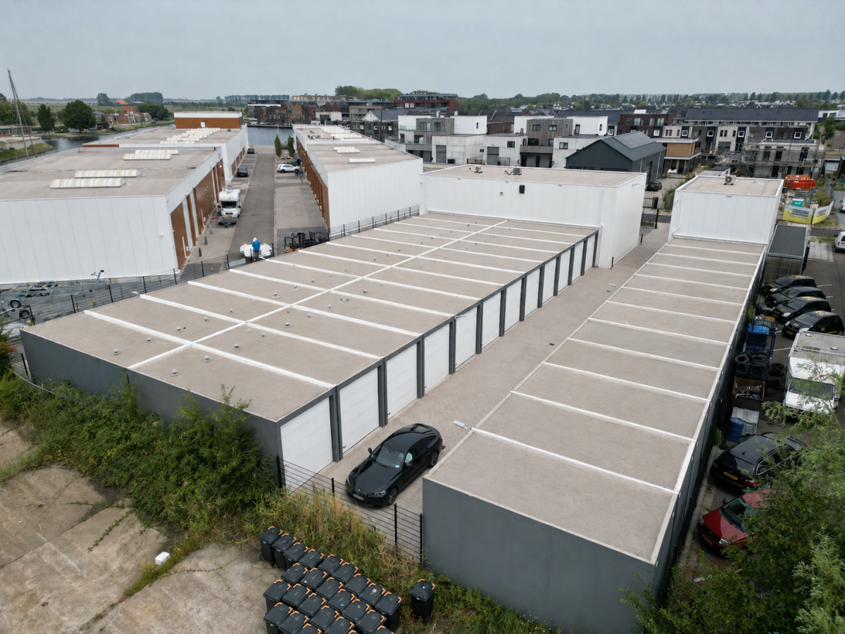 Flachbauten mit Garagentoren und flachen Dächern, umgeben von Grünflächen und Straßen.
