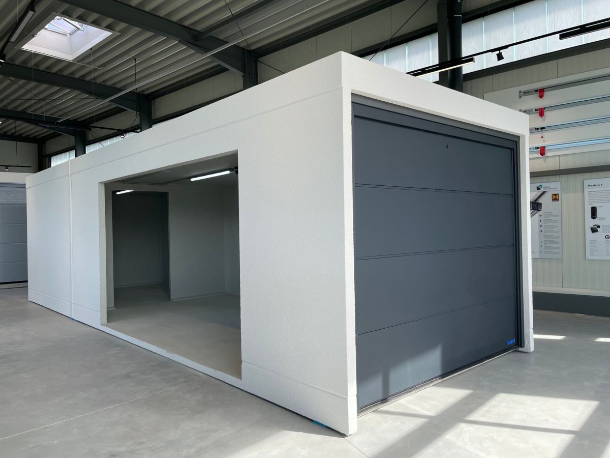 Innenaufnahme eines weißen, rechteckigen Garagenbaus mit geöffnetem Rolltor. Im Hintergrund weitere Garagen und eine Lichtkuppel.