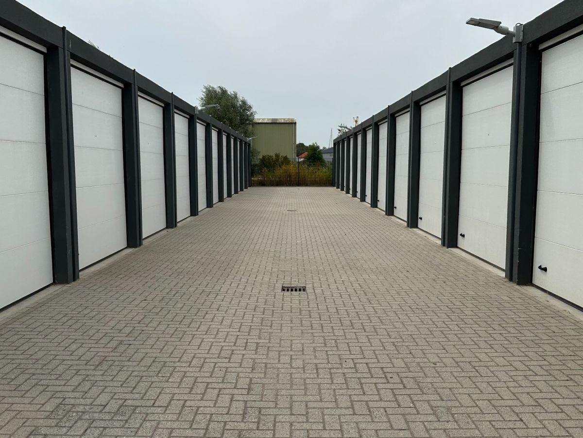 Reihe von weißen Garagentoren mit grau gepflastertem Weg davor.