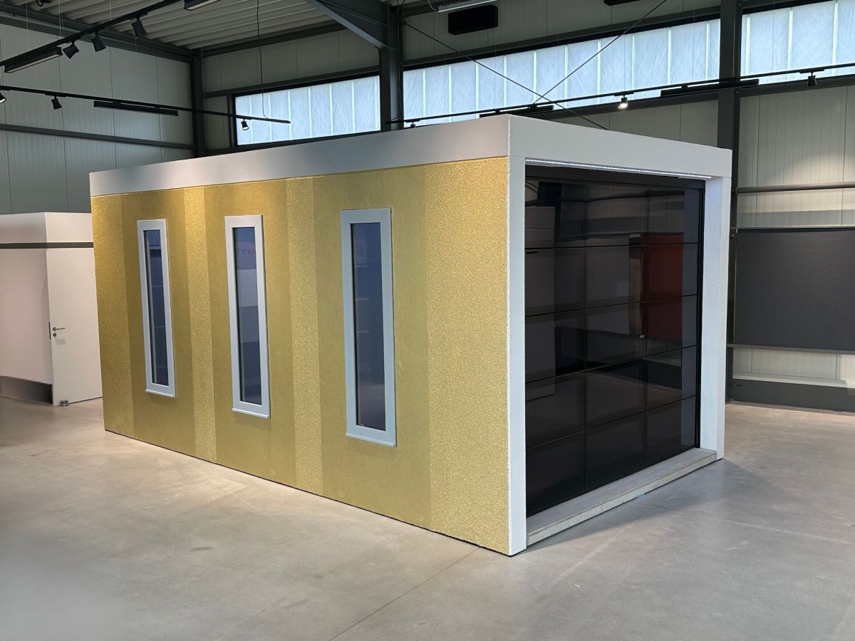 Gelber Schallschutzkabinen-Prototyp mit schmalen Fenstern in einem Lagerhallenraum.