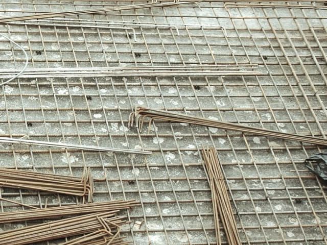 Metallgitter und Bewehrungsstahl auf einer Betonfläche. Baustelle.