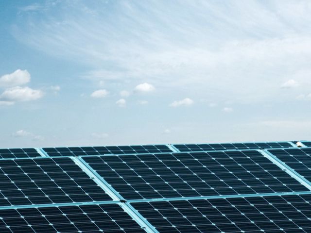 Solarpanel-Anlage unter blauem Himmel mit wenigen Wolken.