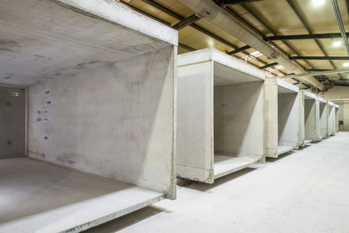 Reihe von Betonelementen in einem Lagerhalleninneren, Rohbauzustand, Deckeninstallationen sichtbar.