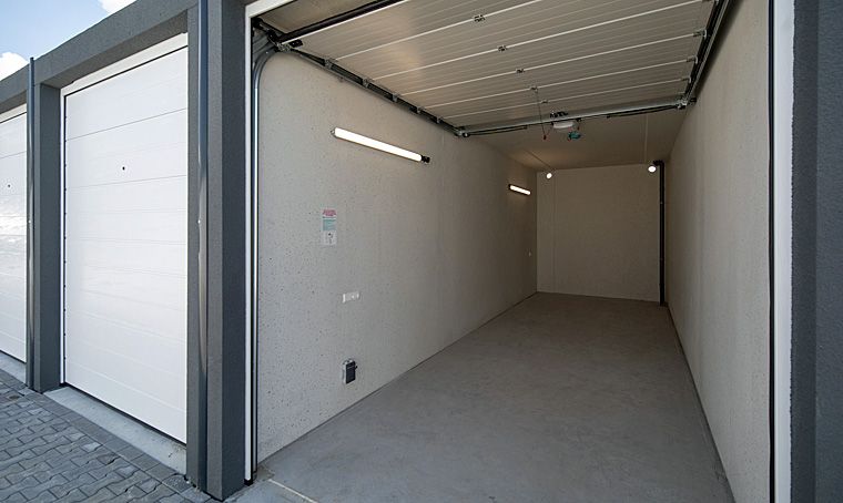 Helle Lagerhalle mit geöffnetem Rolltor. Innenwände und Boden sind hellgrau. Beleuchtung an der Decke.