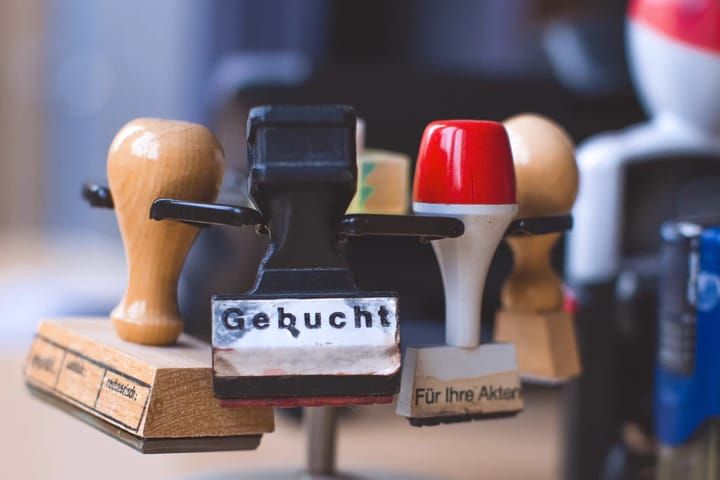 Mehrere Stempel liegen übereinander. Vorderster Stempel zeigt den Text 'Gebucht'.