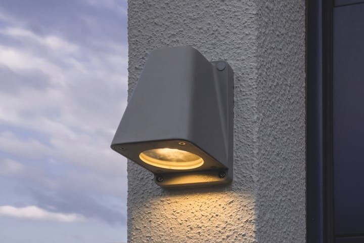 Wandleuchte PYRA aus silbernem Aluminium, montiert an der Außenwand einer Fertiggarage, sorgt für klassische und effiziente Beleuchtung.